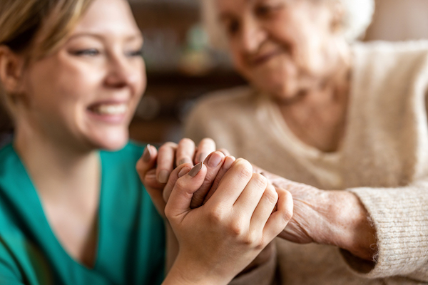caregiver and elderly woman holding hands